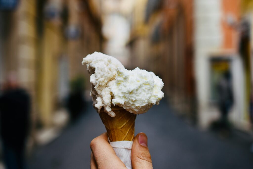 Delicious ice cream cone held up in a blurred urban background, ready to enjoy.